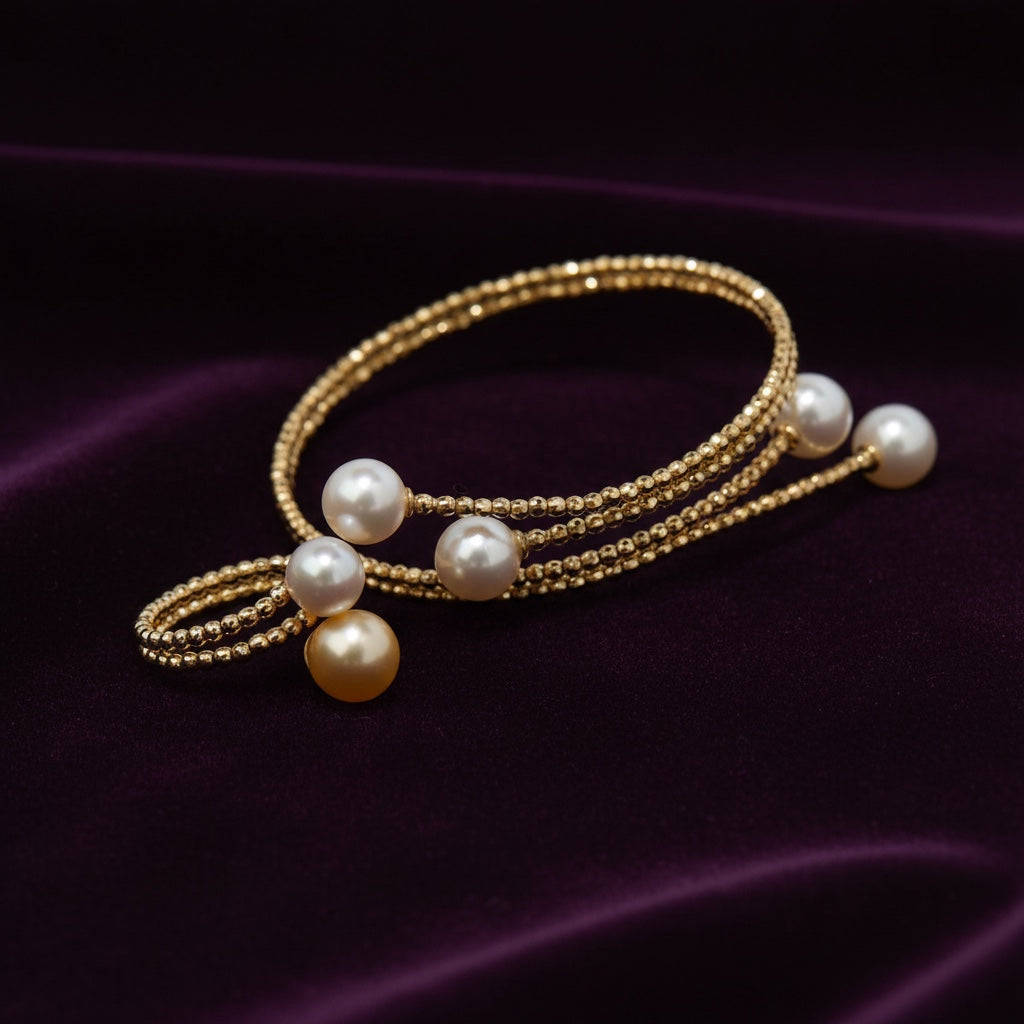 BoxUnboxed Signature Multi-Coil 18K gold bangle with Akoya pearls and a golden pearl accent. Features diamond-faceted beads.