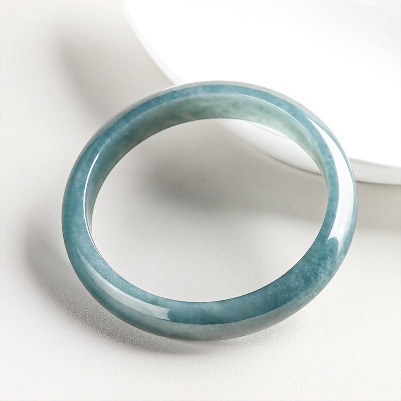 BoxUnboxed Meridian Natural Blue Water Jadeite Bangle, a smooth, translucent ocean-teal bracelet with a high-gloss finish.