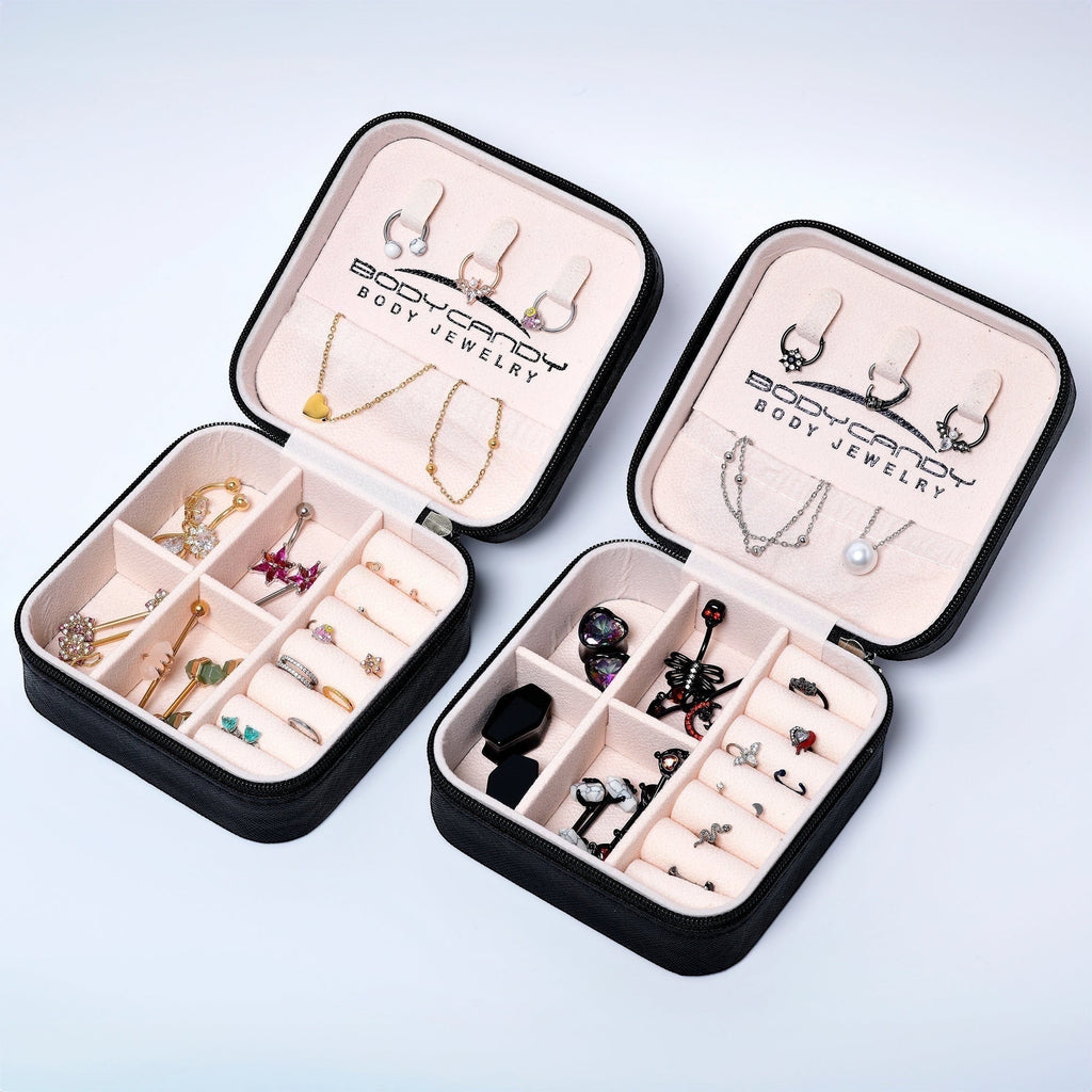 Black BoxUnboxed travel jewelry organizer with pink velvet interior, holding various body jewelry including earrings, necklaces, rings, and belly button rings.